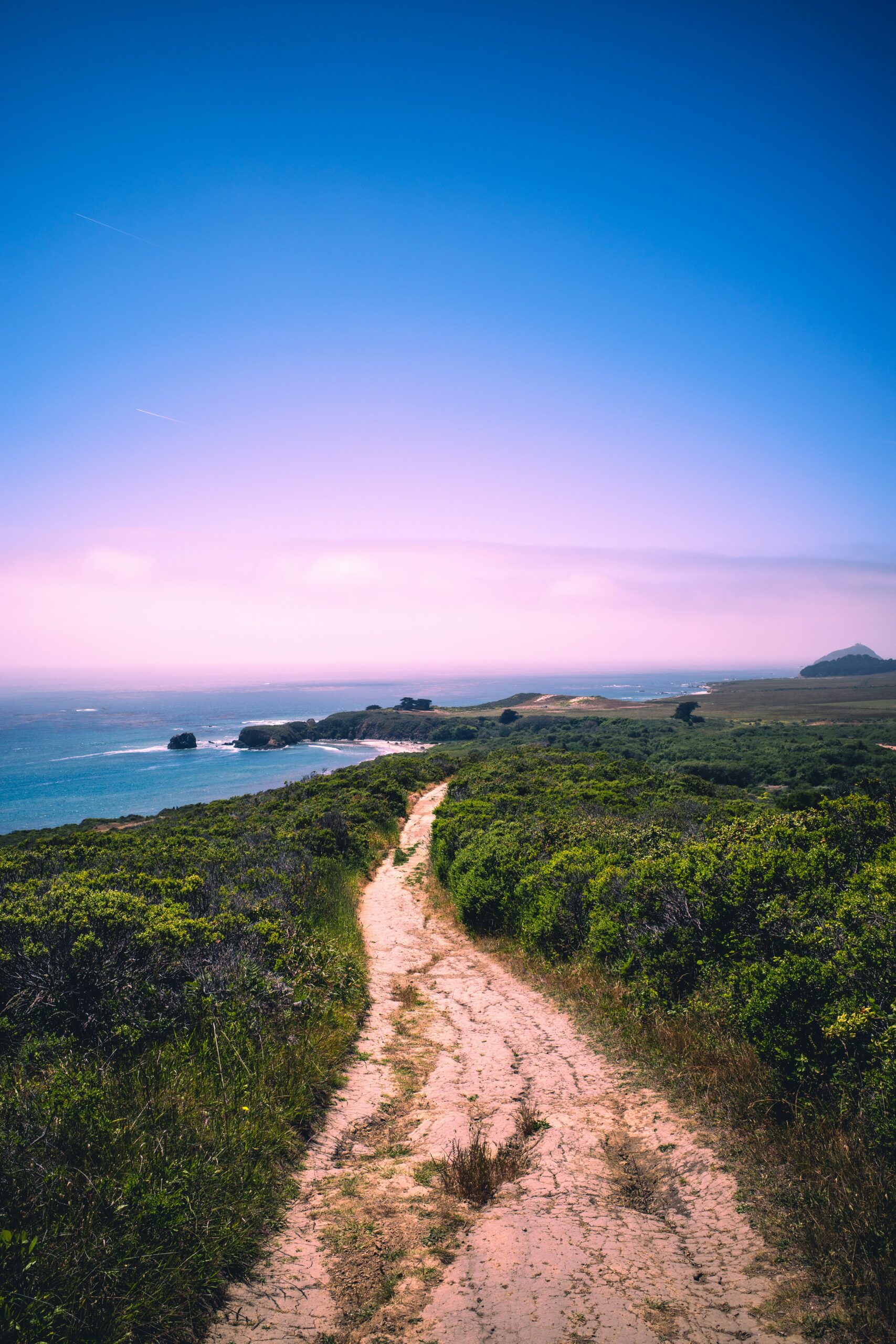 A beautiful winding path leading toward a bright, open horizon at sunrise.<br />
