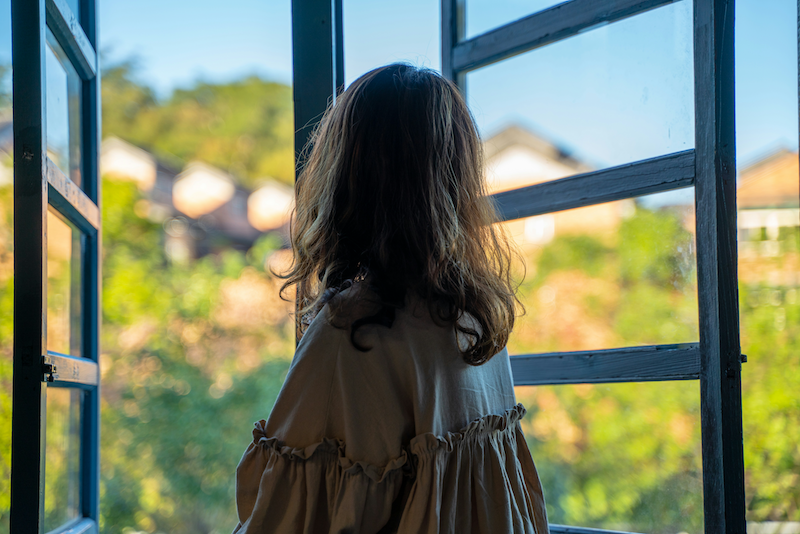 Woman feeling safe looking out of a window.